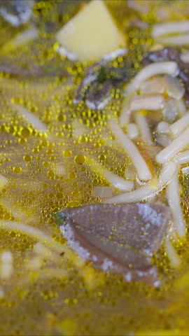 Closeup of flavorful noodle dish. Hot broth with mushrooms and herbs captured in detail. Vivid macro shot of savory mushroom noodle soup with floating ingredients