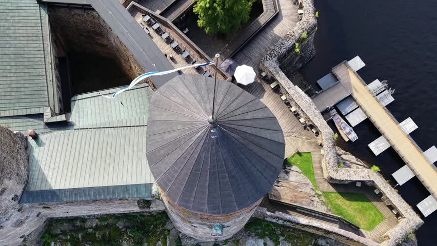 Aerial panoramic view of medieval Olavinlinna Castle surrounded by Lake Saimaa under a blue sky in Savonlinna, Finland.