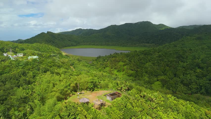 Aerial view over Grand Etang crater lake and dense rainforest canopy revealing wooden observation tower and gazebo at Morne LaBaye lookout in Grenada