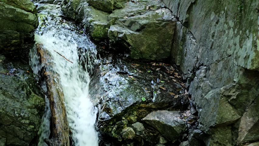 Small Waterfall Flowing Over Rocky Stream in Refreshing Natural Scenery