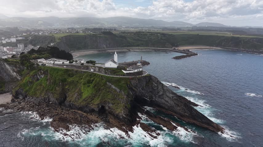 Aerial view of a rocky headland with a lighthouse above a harbour