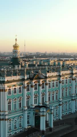 Aerial view flying over the winter palace, home of the hermitage museum, revealing its stunning architecture and the cityscape of saint petersburg, russia, during a golden sunrise