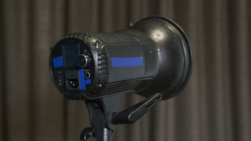 man connecting cable to studio light close-up shot with hands adjusting professional lighting equipment, production setup process for photo or video shoot in indoor studio environment