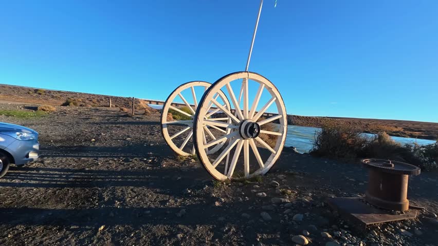A static shot of antique wooden cart wheels displayed outdoors in a sunny, rustic desert environment.
