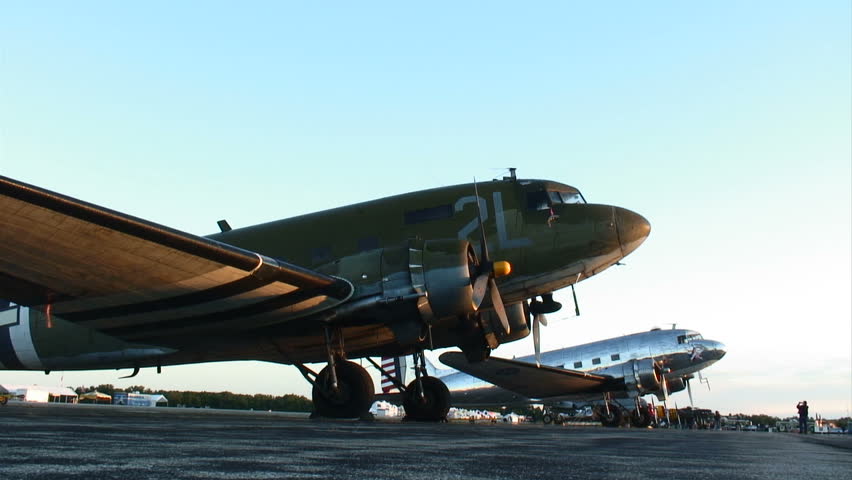 Two Douglas C-47's sitting on an airfield as the sun comes up.