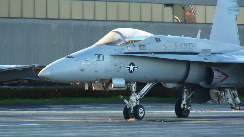 Modern fighter jet standing at an airfield in the early morning sunlight.