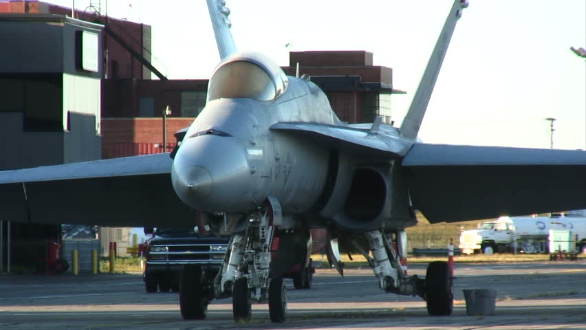 Modern fighter jet standing at an airfield in the early morning sunlight.
