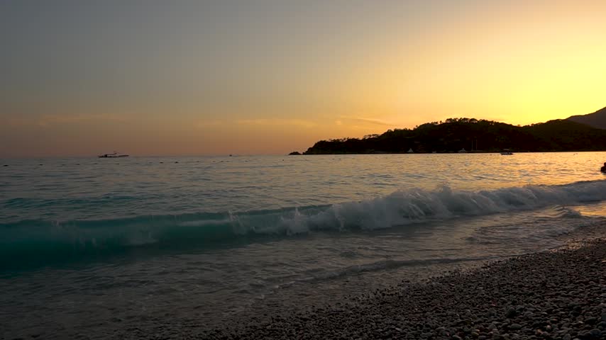 The setting sun casts golden light on the seashore of a tropical resort