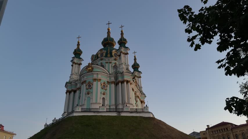 St. Andrew’s Church in Kyiv, Ukraine, featuring Baroque architecture, turquoise and white facade, golden details, onion domes and crosses under a clear blue sky.