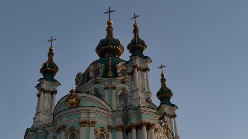 St. Andrew’s Church in Kyiv, Ukraine, featuring Baroque architecture, turquoise and white facade, golden details, onion domes and crosses under a clear blue sky.