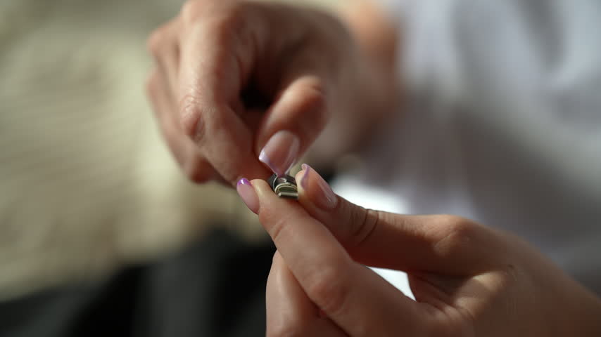 Close-up of female hands repairing damaged charging cable, wrapping frayed wire with insulating tape for quick and effective do it yourself fix of electronic equipment. Shooting in slow motion.