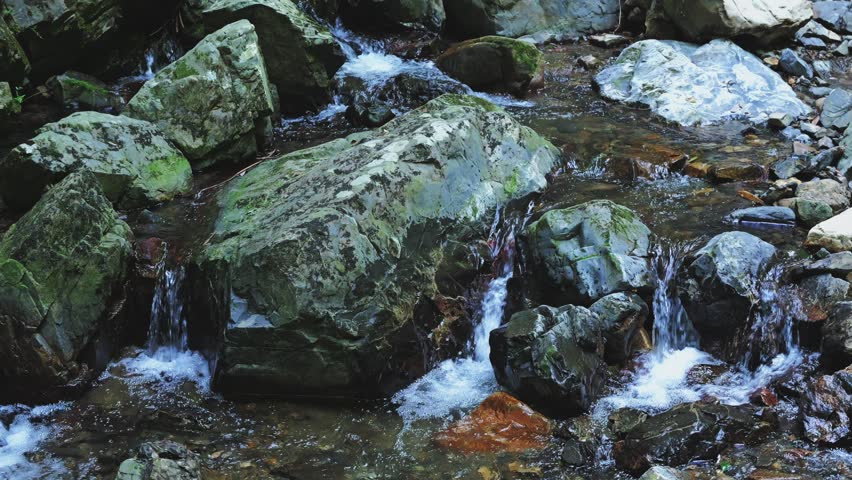 Small Waterfall Cascading Between Rocky Cliffs in a Cool Natural Gorge