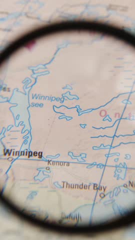 A hand-held magnifying glass moves across a printed map, focusing on a location marked by a colored pin. The destination highlighted is Rotterdam.