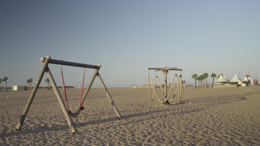France, Valras Plage 08.08.2026 — Empty Children Playground with Wooden Swings on Sandy Beach at Morning