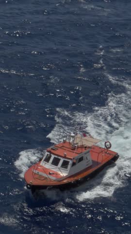 Slow motion vertical view of a small pilot boat speeds through the water while guiding a larger vessel through the Port of Havana, Cuba. 15302