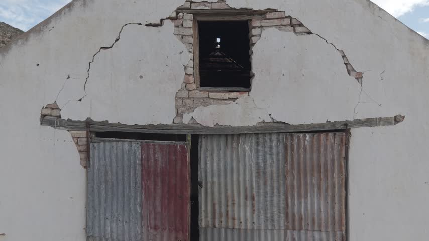 Atmospheric view of abandoned buildings with weathered walls and broken windows, symbolizing decay, forgotten history, and urban exploration themes in rural or industrial landscapes.
