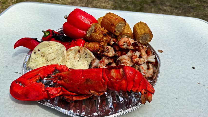 Seafood Boil Platter With A Whole Cooked Lobster, Shrimp, Roasted Red Bell Peppers, And Corn On The Cob. - closeup shot