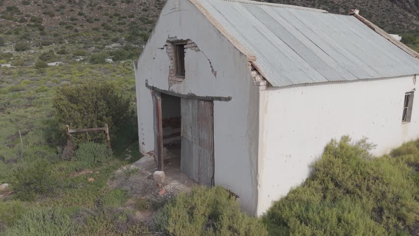 Atmospheric view of abandoned buildings with weathered walls and broken windows, symbolizing decay, forgotten history, and urban exploration themes in rural or industrial landscapes.
