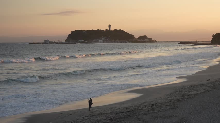 Sunset view of Shichirigahama Beach with Enoshima Island and waves along the Shonan coast in Kamakura, Kanagawa, Japan.