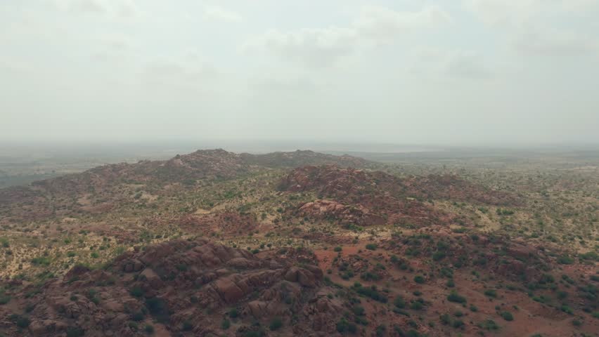 Rocky hills rise from a semi arid plain in the Thar Desert of Sindh, filmed by drone.