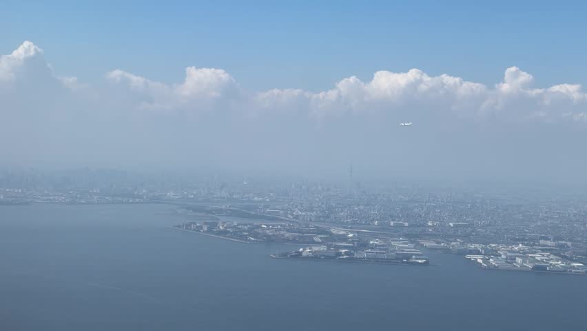 Aerial view of Tokyo Bay in Japan with city skyline and distant clouds