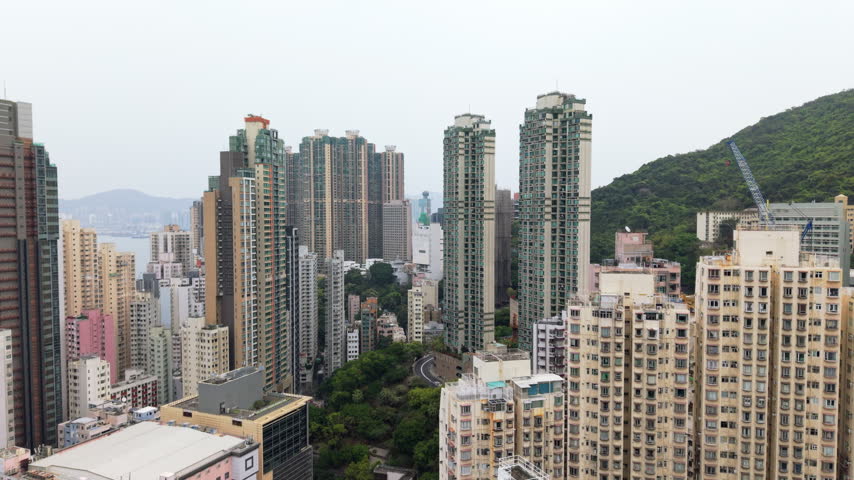 Hong Kong Urban Sprawl Showcasing High-Rise Residential Buildings And Distant Mountains Across Water. Dense Urban Landscape Of Hong Kong Revealing Residential Buildings, Architectural Diversity, And