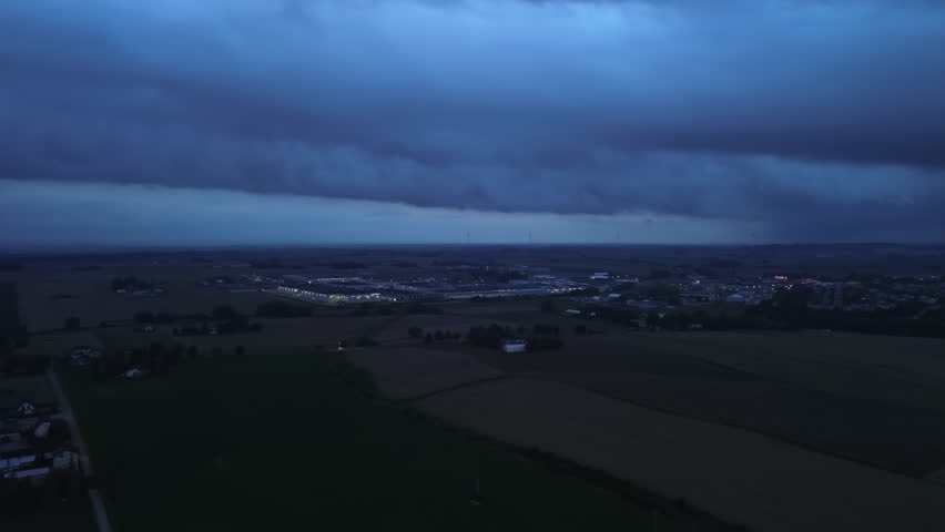 Storm Clouds Over Rural Farmland and Large Industrial Facility at Dusk