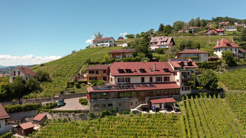 Low-altitude flight over Grandvaux in the UNESCO-listed Lavaux Vineyard Terraces overlooking Lake Geneva, highlighting traditional village life and modern solar panel integration.