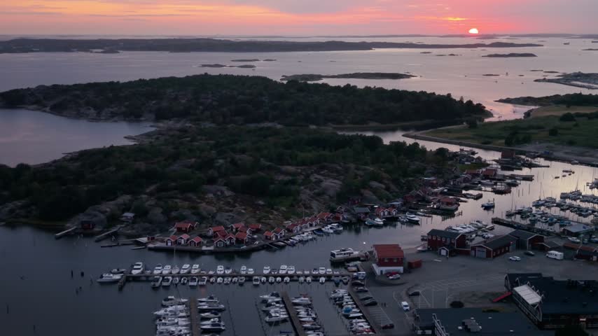 Aerial view of Onnereds Brygga marina with red wooden houses and boats docked in the harbor during a golden sunset in Gothenburg, Vastra Gotaland County, Sweden.