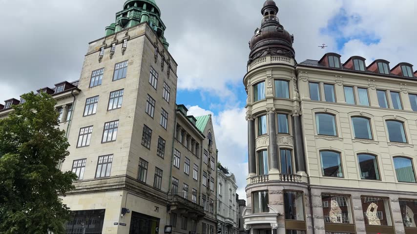 Historic corner buildings on the Gammeltorv square in center of Copenhagen, bottom view while vertical panning of upper floors with different green and dark copper domes on the roofs, Denmark 

