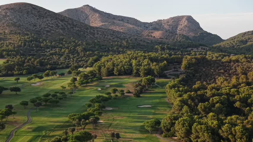 Golf course and resort lifestyle concept, aerial view of green fairways surrounded by lush forests and mountains