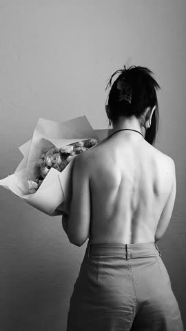 Girl with flowers, black and white, vertical video, back view