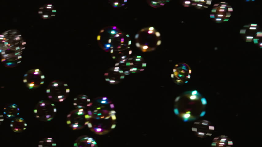 Soap Bubbles Floating on Black Background. A large number of soap bubbles moving in one direction against a black background. Great for use in blending