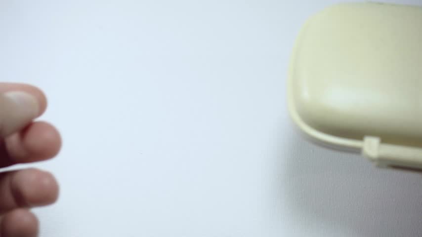Close up of hands opening a pill organizer and showing tablets inside. Medication storage container for organizing daily medicines and supplements at home