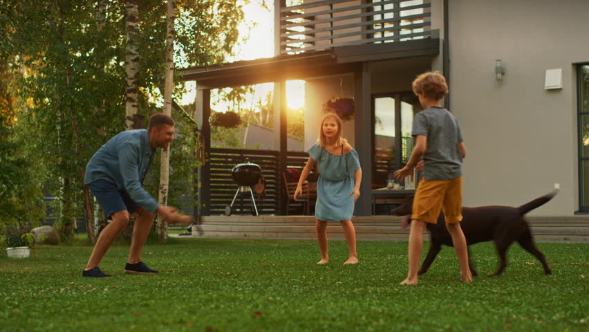 Beautiful Family of Three Play Fetch Toy Ball with Happy Brown Labrador Retriever Dog on the Backyard Lawn. Idyllic Family Has Fun with Loyal Pedigree Dog Outdoors in Summer House