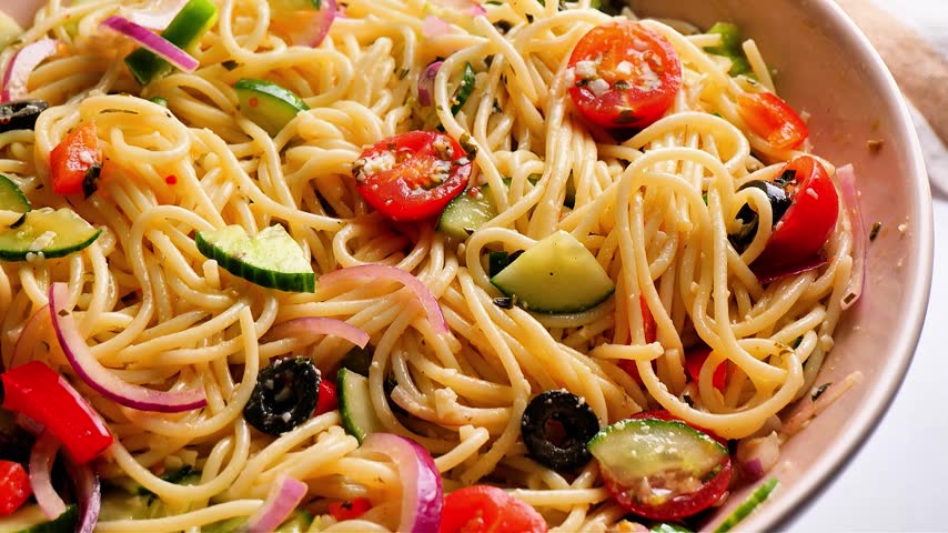 Vegan noodles salad showcases a fresh plant-based meal combining noodles, vegetables, and colorful ingredients for a light Asian-inspired dish. This versatile footage can support vegan restaurant advertising, healthy food campaigns, recipe demonstrations, meal prep content, food photography, wellness marketing, food delivery promotions, catering menus, and culinary storytelling focused on plant-based eating.