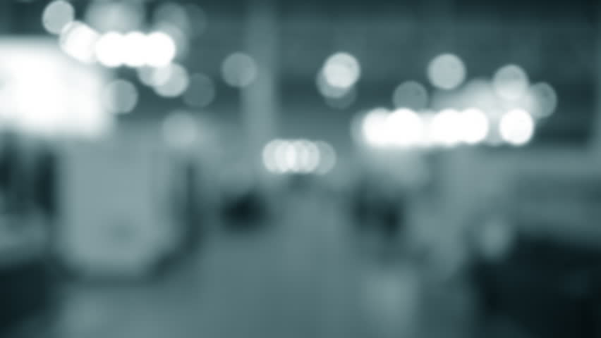 Blurred background. Many people walking inside large building. Men and women walking on floor inside room with high ceiling and large lanterns on walls. Public place. Exhibition presentation backdrop