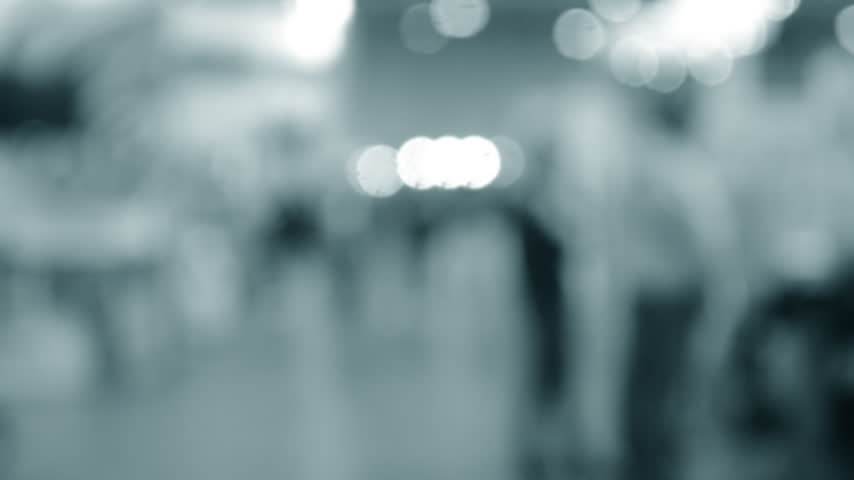 Blurred background. Many people walking inside large building. Men and women walking on floor inside room with high ceiling and large lanterns on walls. Public place. Exhibition presentation backdrop