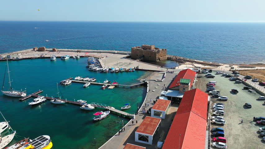 Aerial view of Paphos Castle and harbour in Cyprus. The historic fortress, boats, marina docks and turquoise water create an iconic seaside landmark scene.