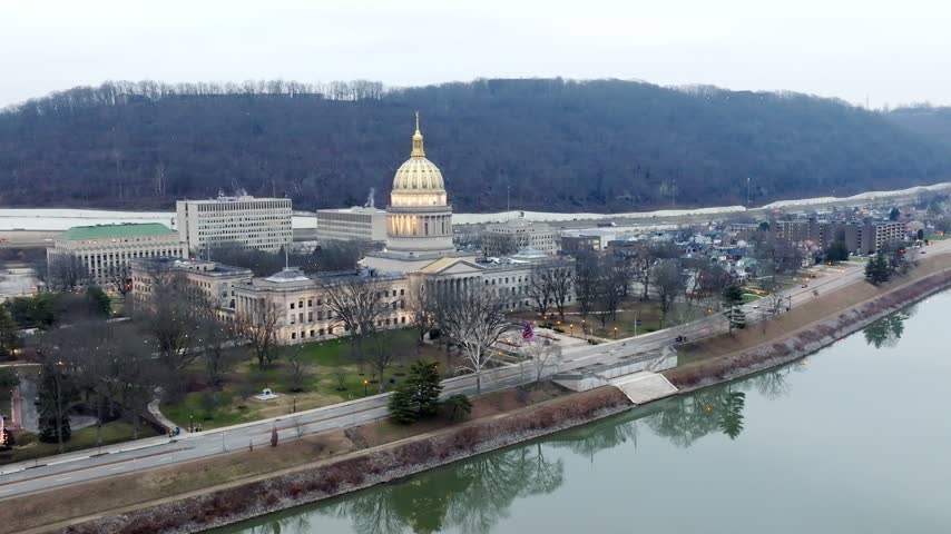 West Virginia state capitol building at dusk in Charleston, West Virginia with drone video moving down.