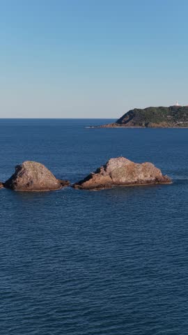 Vertical aerial footage trucking left past Julian Rocks with Byron Bay in the background, Northern Rivers, New South Wales, Australia