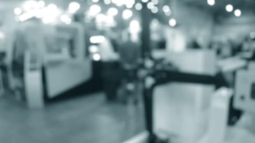 Moving blades. People men standing near equipment machine. Silhouettes of people indoors. Exhibition center. Building with walls, floor, ceiling illuminated lamps. Blurred background. Blue color.