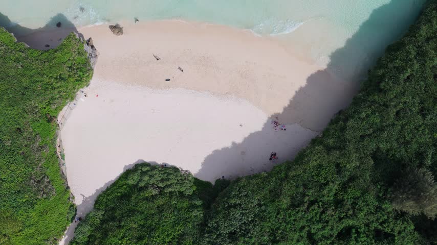 Horizontal aerial footage tilted down while dollying forward above the white sand shoreline and crystal-clear waters of Sunayama Beach and Nikawatori Beach, Miyako, Okinawa, Japan