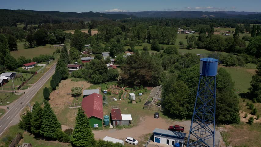 Aerial view of a blue water tower and rural service compound