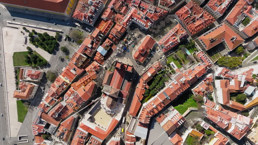 Striking aerial shot of Lisbon’s old town, showcasing dense urban architecture, iconic terracotta rooftops, winding streets, and sunlit city geometry with typical portuguese architecture.