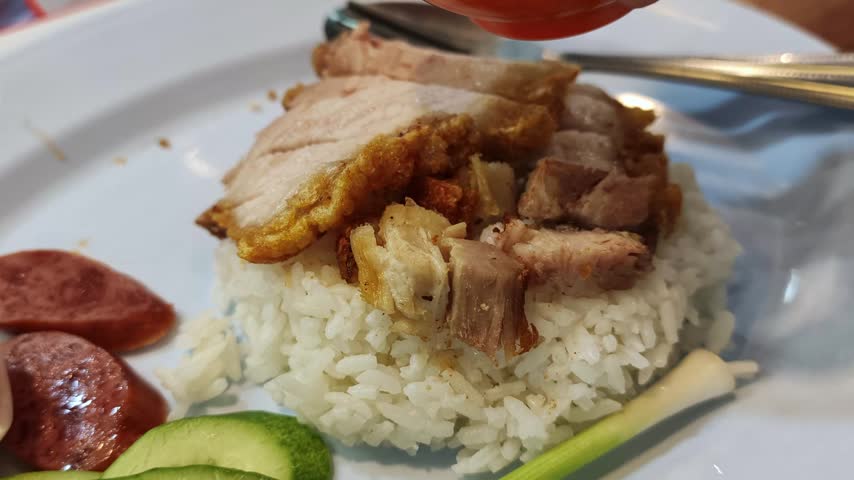 Pouring Sweet Red Sauce Over Thai BBQ Pork and Crispy Pork with Rice