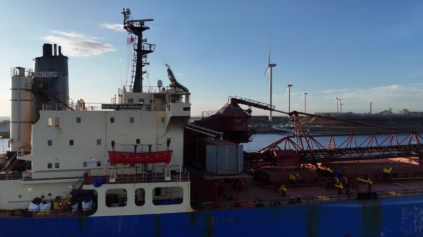 Static drone perspective as bulk carrier moves through frame