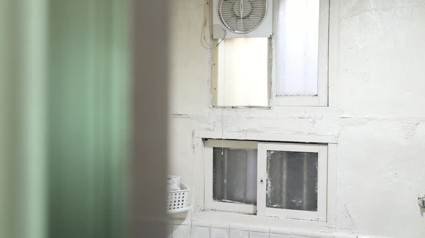 An indoor eye-level shot capturing the weathered interior of an old house in a rural South Korean village. The white-painted wall features classic vintage windows, a small exhaust fan, and white-tiled lower sections, conveying a nostalgic and authentic countryside living environment.