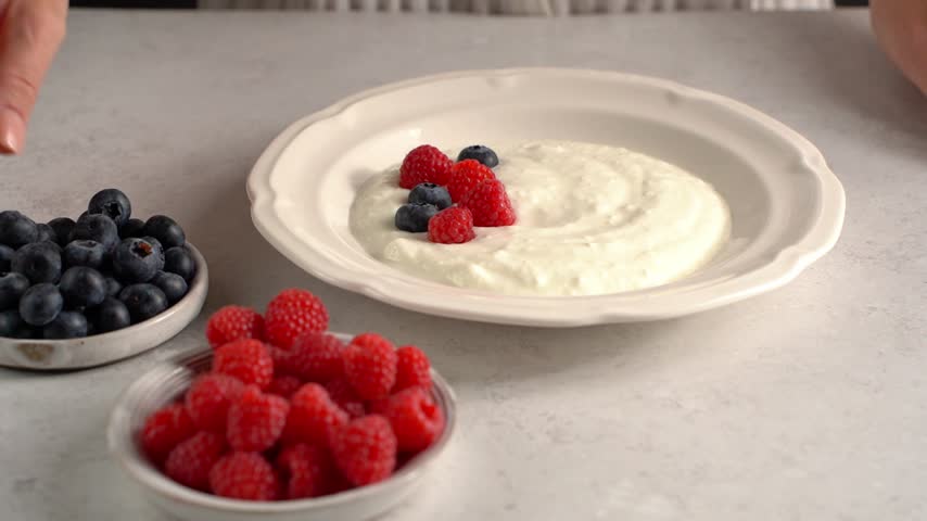 Decorating yogurt with raspberries and blueberries