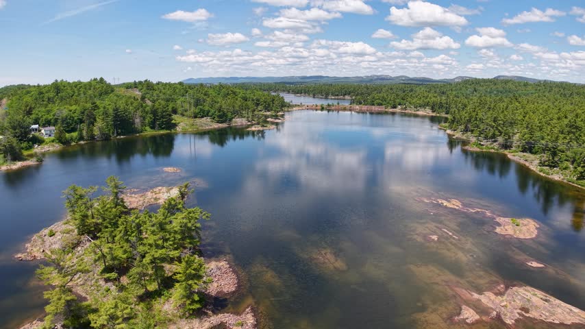 An elevated view surveys forests rocky ridges and inland water across northern Ontario from a high overhead perspective